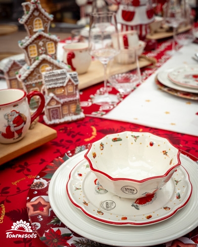 Table de Noël décorée avec vaisselle festive et maisons en pain d'épices.